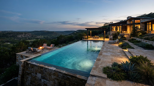Architectural resort-style negative edge swimming pool at a contemporary Texas hill country estate at dusk, crystalline turquoise water with subtle ripples, limestone terrace and native cedar terrain under soft twilight sky.